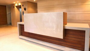 A reception desk with a wooden base and a white top, an elevator, and a wall-mounted phone. - Sagar Residency (Amritsar)