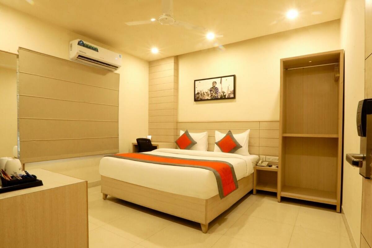 A hotel room with a bed, bedside table, nightstand, and a wardrobe.