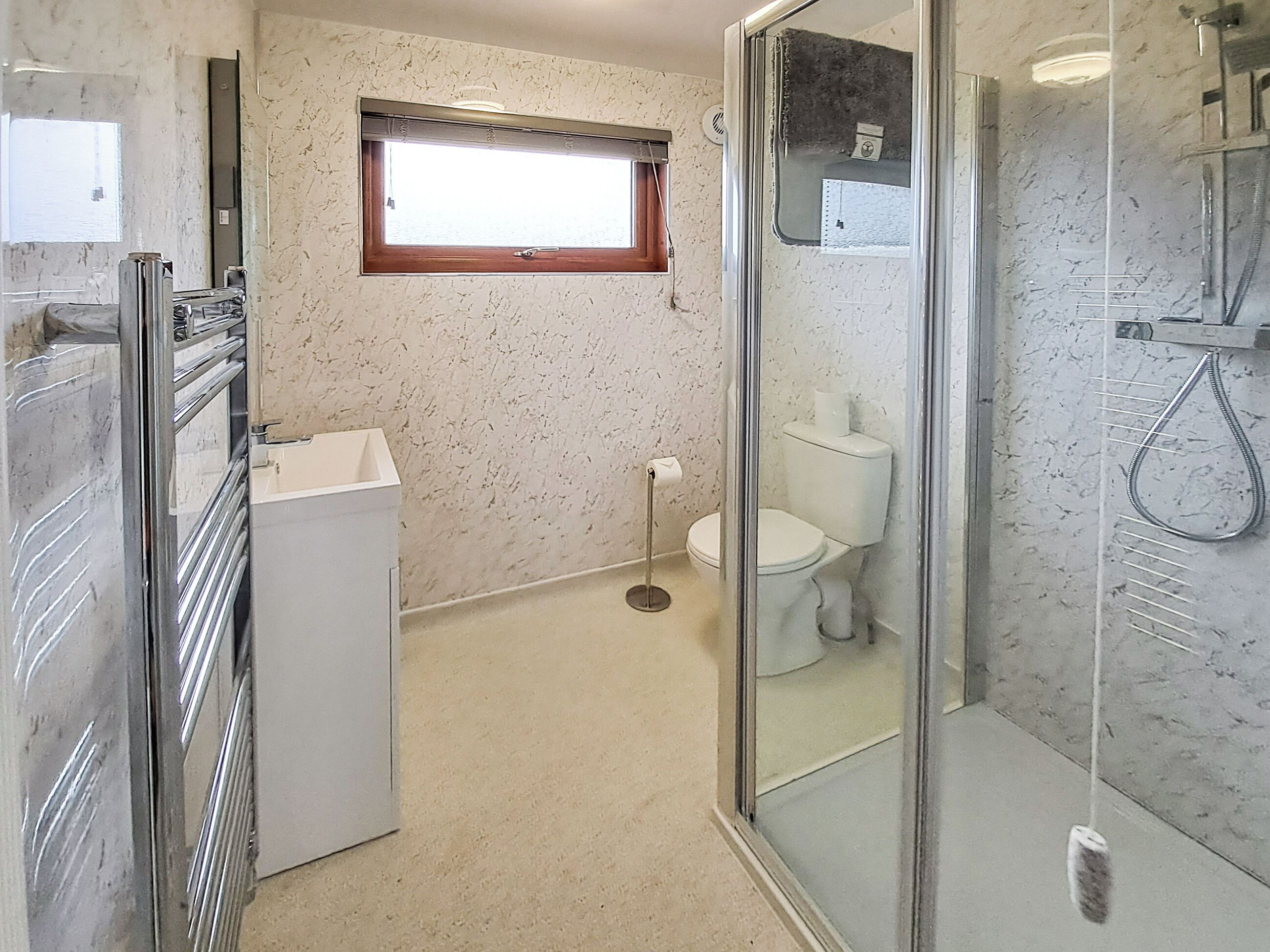 Ein Badezimmer mit Duschkabine, Toilette und Waschbecken mit Spiegel.