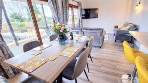 A dining area with a wooden table, chairs, and a vase of flowers.