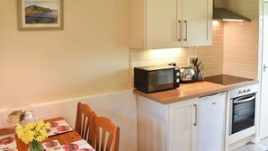 A compact kitchen with white cabinets, a microwave, a toaster, and a small oven.