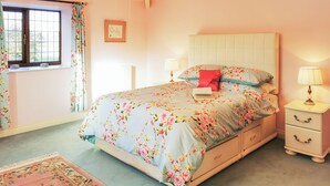 Une chambre à coucher avec un lit, des tables de chevet, une fenêtre et un lustre.