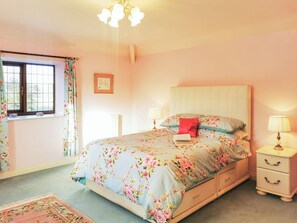 Ein Schlafzimmer mit Bett, Nachttischen, einem Fenster und einer Chandelier.