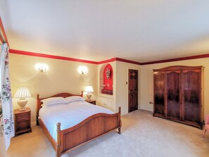 Een slaapkamer met een houten bed, nachtlampjes, een kledingkast en een spiegel.