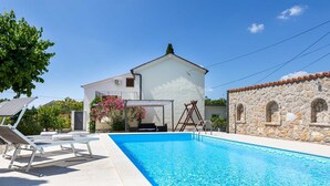 A swimming pool with lounge chairs, a white building with a stone wall, and a clear blue sky. - Charming holiday house Antica with private swimming pool (Rasopasno (Krk))