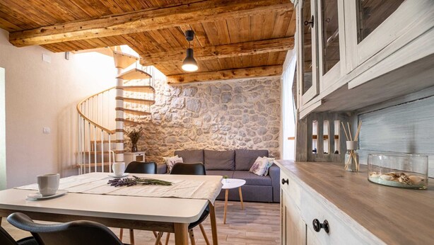A cozy interior with a dining area, stone wall, wooden ceiling, and a staircase. - Charming holiday house Antica with private swimming pool (Rasopasno (Krk))