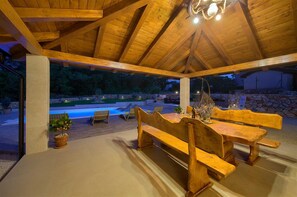 Un pabellón de madera al aire libre con piscina, sillones de descanso y una mesa de comedor.