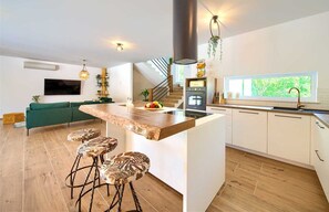 Enjoy meals at the central island with bar stools, surrounded by white cabinetry and an oven.
