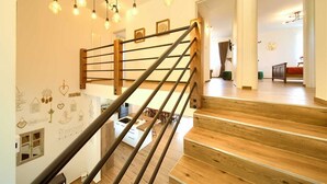 A staircase with wooden steps and a metal handrail, leading to a room with a dining area and a bed. - Beautiful Villa Green Pearl with heated pool (Gostinjac (Krk))