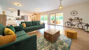 A modern living room with a green sofa, a wooden coffee table, and a bicycle in the background. - Beautiful Villa Green Pearl with heated pool (Gostinjac (Krk))