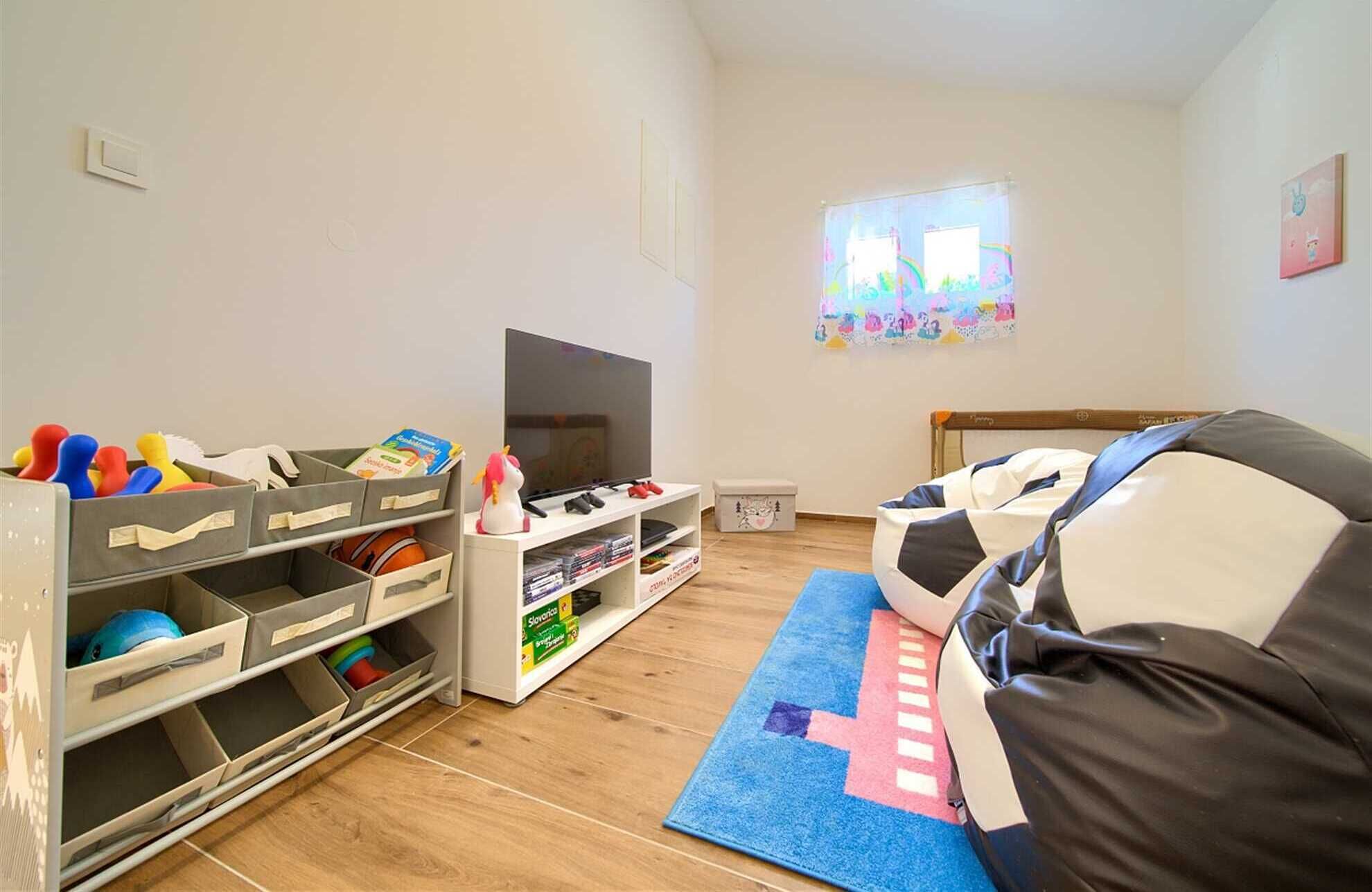 En stue med fjernsyn, opbevaringsenheder, en sofa og et vindue med udsigt.