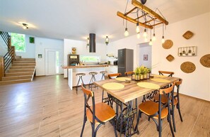 Una cocina moderna con una isla central, suelo de madera y un comedor con mesa y sillas de madera.