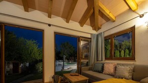 Una sala de estar acogedora con un sofá, una mesa de centro y ventanas amplias con vistas al exterior.
