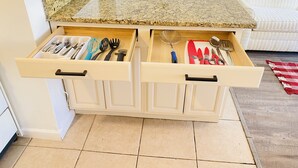 A kitchen with two drawers containing utensils and a countertop with a granite top.