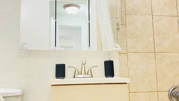 Ein Badezimmer mit Toilette, Waschbecken, Spiegel, Dusche und Badewanne.