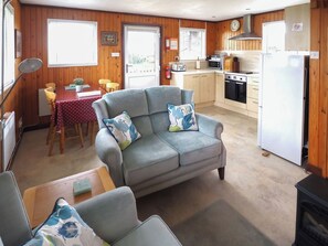 A cozy living room with a sofa and armchairs, a dining area with a table and chairs, and a kitchen with appliances.