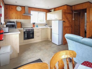 A kitchen with wooden cabinets, a microwave, a toaster, a sink, and a refrigerator.