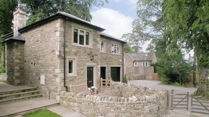 A stone building with a stone wall, steps, a bench, and a gate.