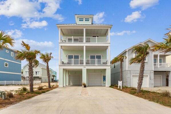 Un bâtiment à deux étages situé en bord de mer, doté d’un balcon à l’étage supérieur, d’un garage et offrant une vue sur un ciel dégagé.