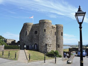 Un château de pierre historique, orné d’un drapeau, avec un chemin pavé et un lampadaire.