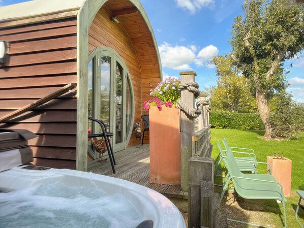 A wooden cabin with a hot tub, outdoor seating, and a garden.