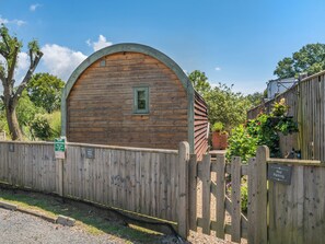 Un bâtiment en bois doté d’un toit incurvé, d’une petite fenêtre et d’une clôture en bois.