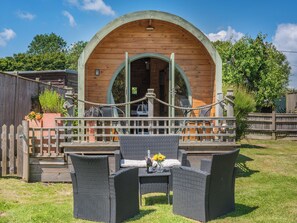 A wooden cabin with an arched entrance, a covered patio with wicker furniture, and a rope barrier. - 1 bedroom accommodation in Northiam, near Rye (Northiam, near Rye)