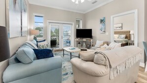 A living room with a ceiling fan, a TV, and a balcony with outdoor furniture.