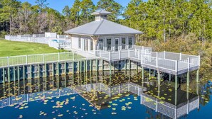 A waterfront property with a house on stilts, connected by a bridge with a white railing.