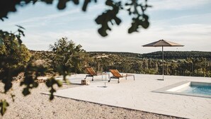 A poolside area with lounge chairs and an umbrella, surrounded by a natural landscape. - Villa Terra Meera (Skradin)