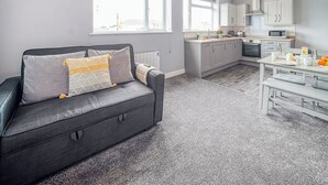 Una cocina moderna con armarios blancos, un microondas y un comedor con una mesa dispuesta para dos.