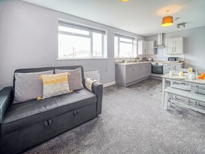 Een moderne keuken met witte kasten, een magnetron en een eethoek met een tafel gedekt voor twee personen.