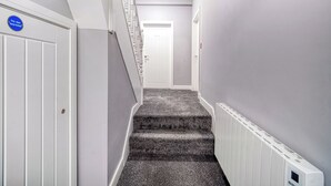 Un estrecho pasillo con una escalera empapelada que conduce a una puerta.