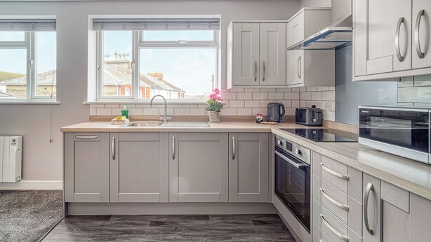 Una cocina moderna con armarios grises, un horno de acero inoxidable y una ventana con vista a edificios.