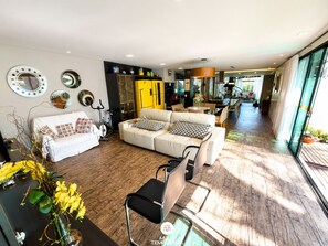 A modern living room with a sofa, a dining area, and a kitchen in the background.