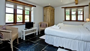 A bedroom with a bed, a television on a small table, a chair, and a wardrobe. - 2 bedroom accommodation in Chulmleigh (Chulmleigh)
