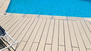 Une piscine rectangulaire à l’eau d’un bleu limpide, entourée d’une terrasse en bois.