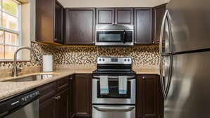 Une cuisine moderne avec des meubles en bois foncé, des appareils électroménagers en acier inoxydable et un dosseret décoré.
