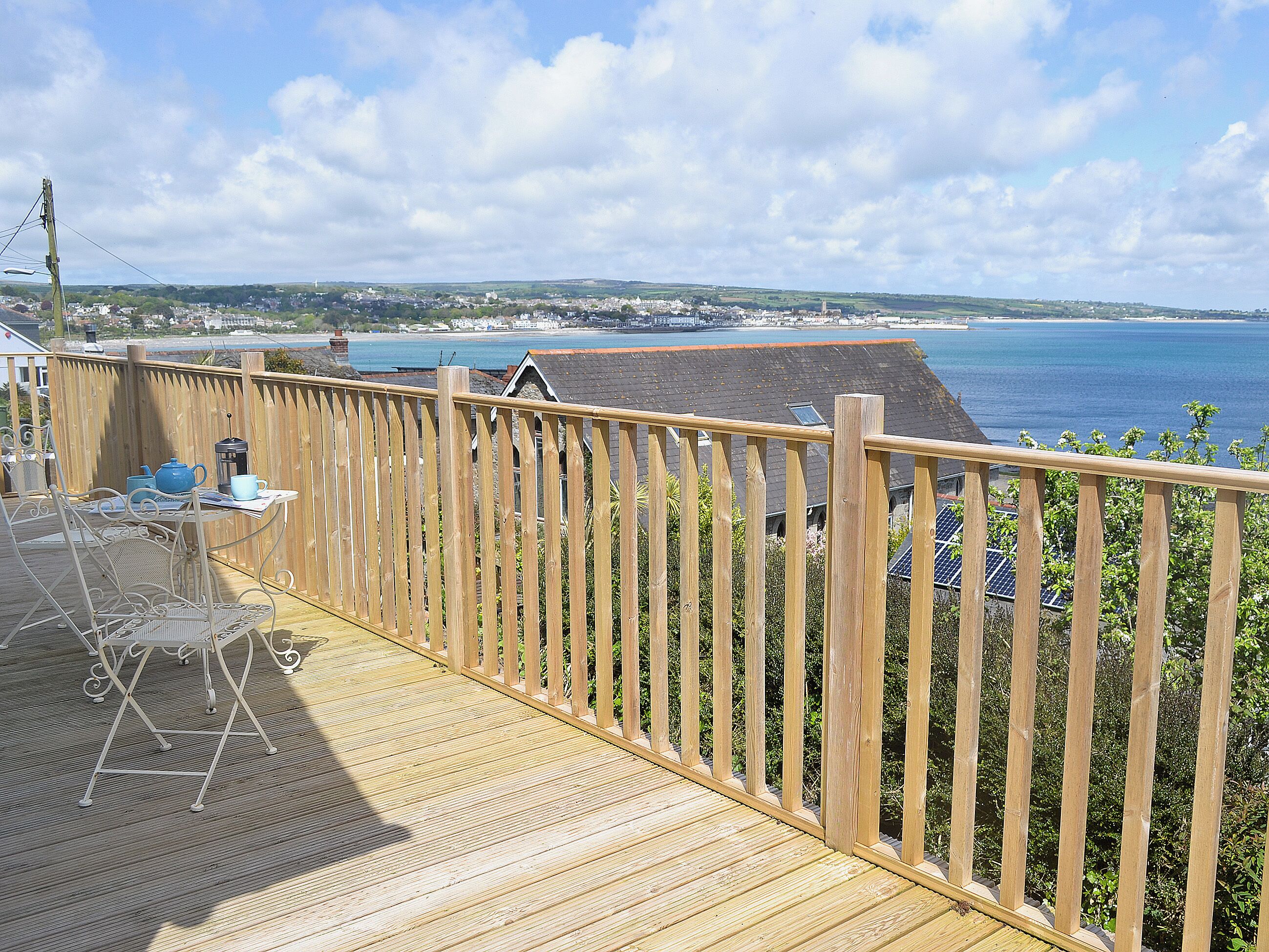 Eine Holzterrasse mit Blick auf das Meer und eine entfernte Stadt.