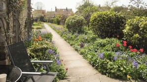 A garden pathway with a stone wall on one side and a variety of flowers and shrubs on the other. - Eden House Holiday Cottage (Pickering)