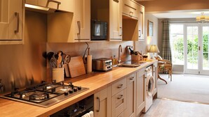 A modern kitchen with a stove, oven, microwave, and a washing machine. - Eden House Holiday Cottage (Pickering)