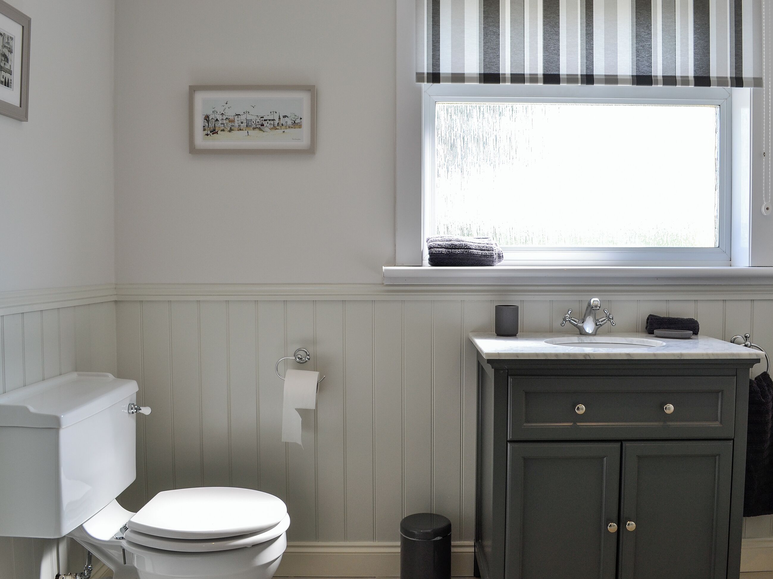 Une salle de bain avec des toilettes, un lavabo et une fenêtre.