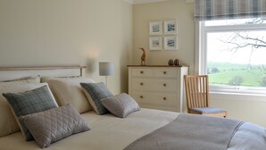 A bedroom with a bed, a dresser, a chair, and a window with a view.