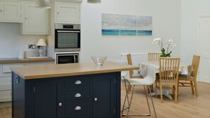 A modern kitchen with a central island, built-in oven, and white cabinetry.