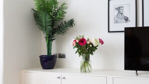 Un meuble blanc sur lequel sont posés un pot de fleurs et un vase rempli de fleurs.