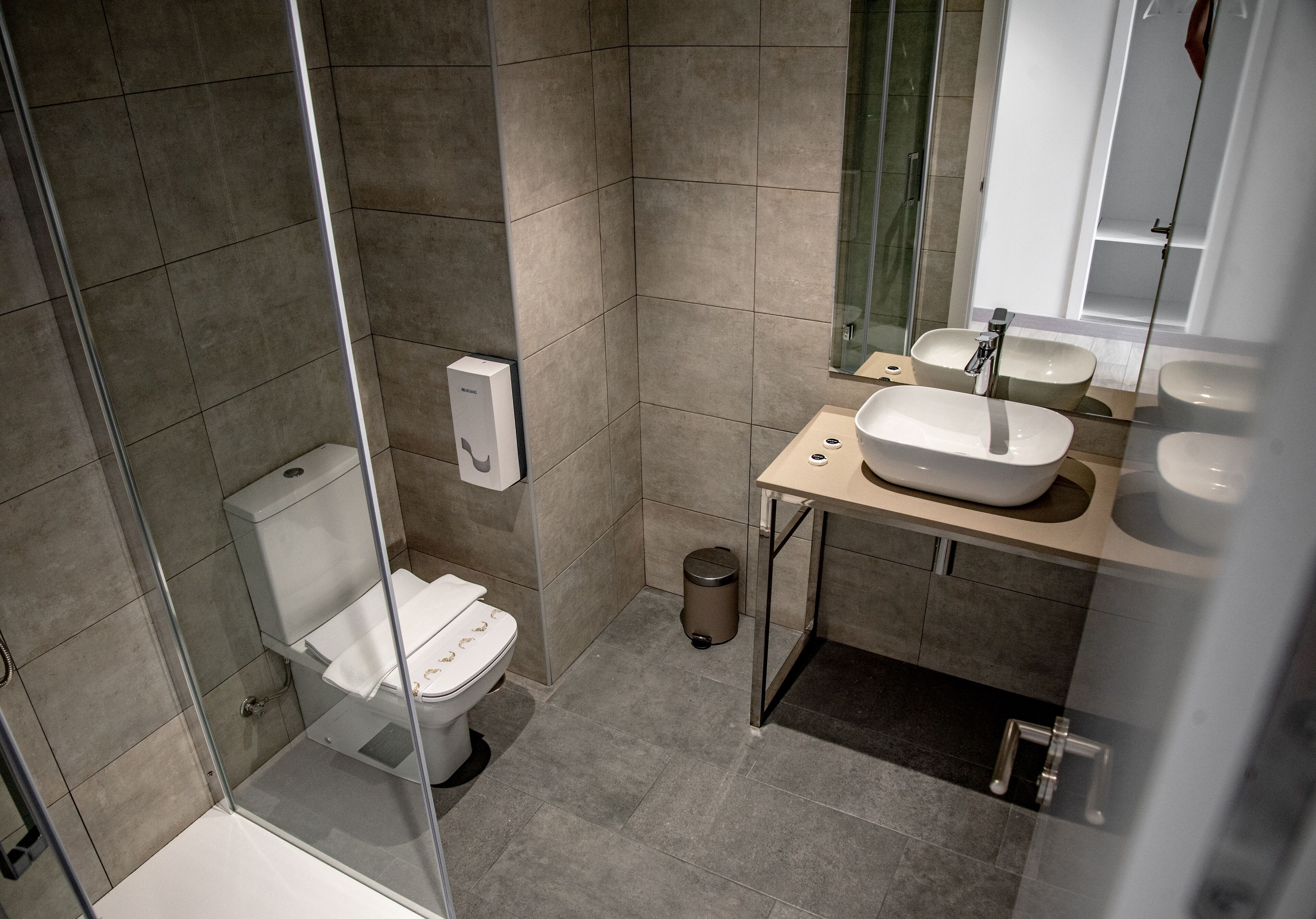 Ein modernes Badezimmer mit einer gläsernen Dusche, einer Toilette und einem Waschtisch mit zwei Becken.