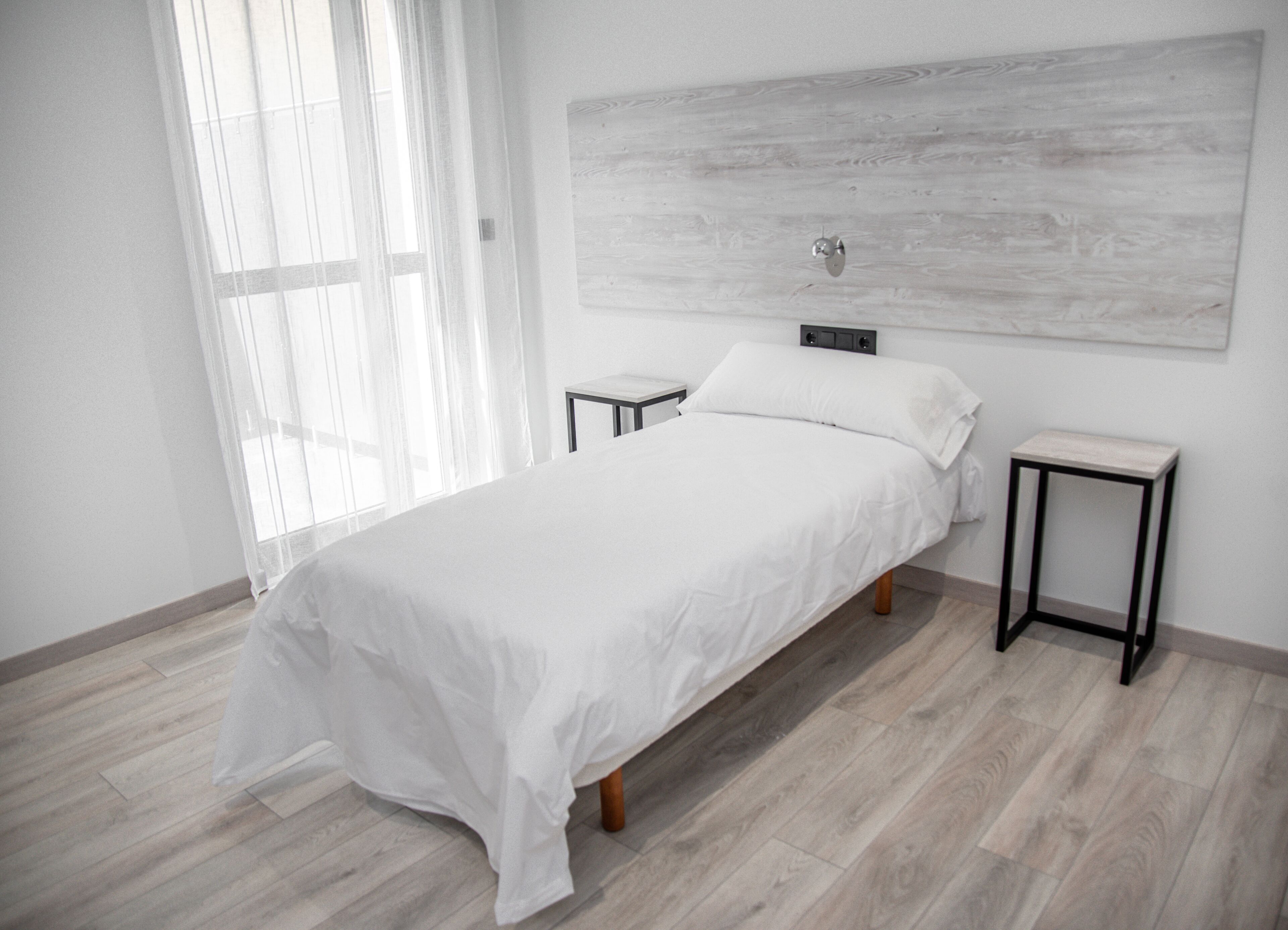 A modern bedroom with a large bed, bedside tables, and a wooden floor.