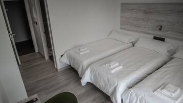 A hotel room with two beds, a green chair, and a remote control on a table.
