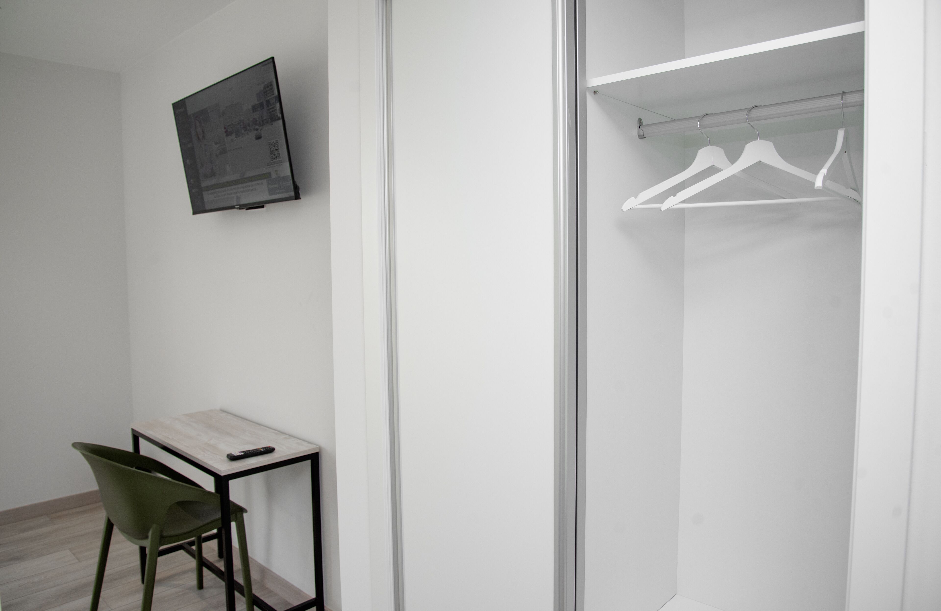 A modern room with a desk, chair, and a closet with white hangers.