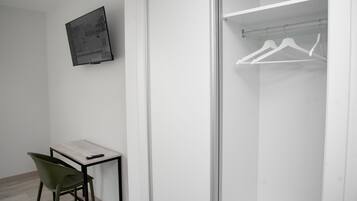 A modern room with a desk, chair, and a closet with white hangers.